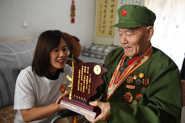 吉林省退役軍人事務(wù)廳工作人員向老兵徐洪英贈送榮譽紀念牌。