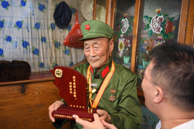 省退役軍人事務(wù)廳人員向老兵張俊財(cái)贈(zèng)送榮譽(yù)激勵(lì)牌。