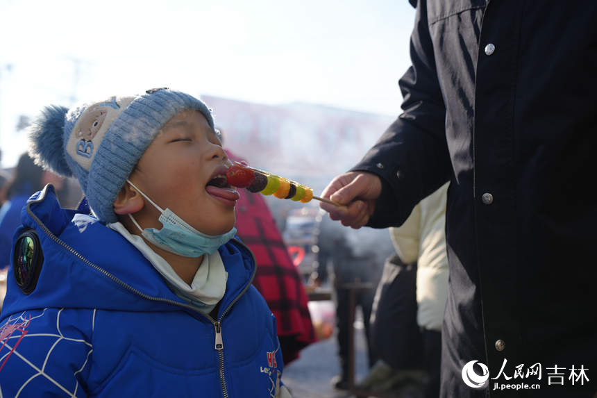 小朋友在大集上品嘗香甜的糖葫蘆。人民網(wǎng)記者 李洋攝