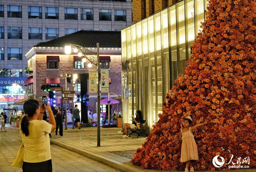 一名小朋友在春京西文旅街區(qū)打造的鮮花墻前拍照留念。人民網(wǎng)記者 李洋攝