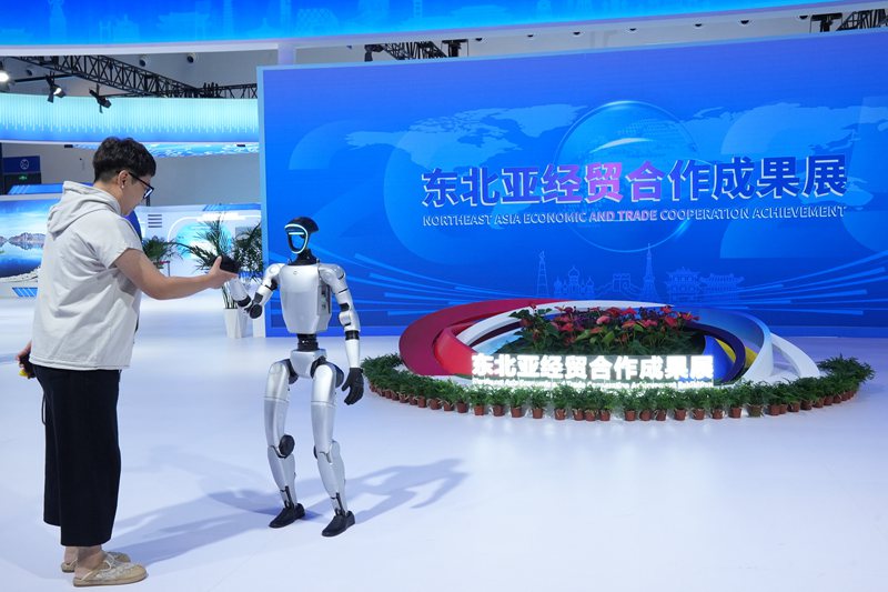 游客在東北亞經(jīng)貿(mào)合作成果展上與機(jī)器人握手。人民網(wǎng)記者 李洋攝