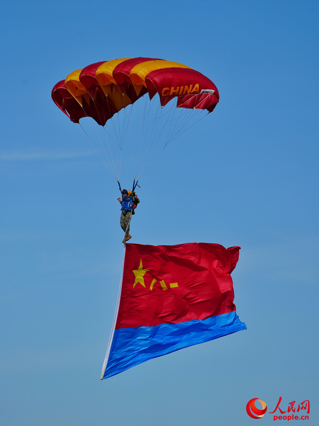 “八一”“藍鷹”跳傘隊攜帶黨旗、國旗、八一軍旗和空軍軍旗先后躍出機艙,而后,多名跳傘