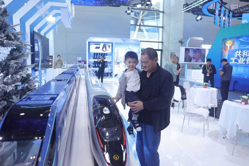 被抱起的小朋友，高興地和高鐵模型來一場“親密接觸”。人民網記者 王海躍攝