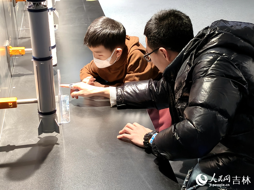 父親帶著孩子近距離觀察長征系列運載火箭模型，探索航天奧秘。劉子銘攝