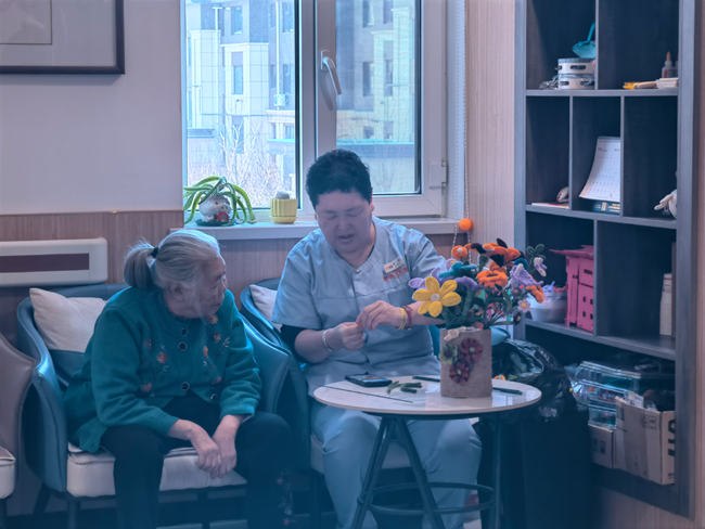 老人在和工作人員學習編織花。人民網記者 馬俊華攝