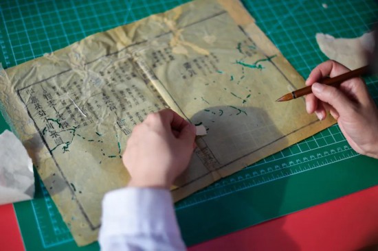 “全國古籍重點保護單位”吉林大學(xué)圖書館內(nèi)館藏古籍近40萬冊，其中善本書6000余部。學(xué)校自20世紀(jì)50年代便開始進行古籍整理修復(fù)工作，數(shù)十年間從未間斷。圖為4月19日，古籍修復(fù)師為古籍書頁配紙“補洞”。許暢攝